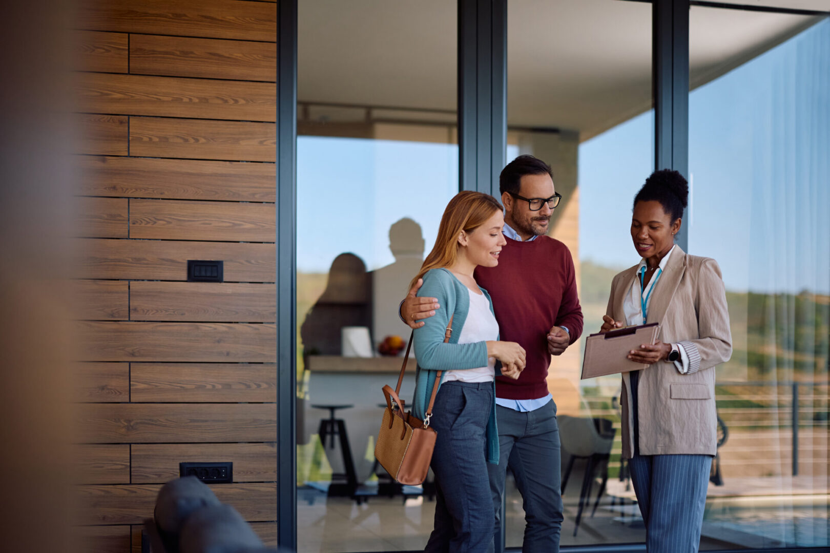Real estate agent with couple outside modern home.