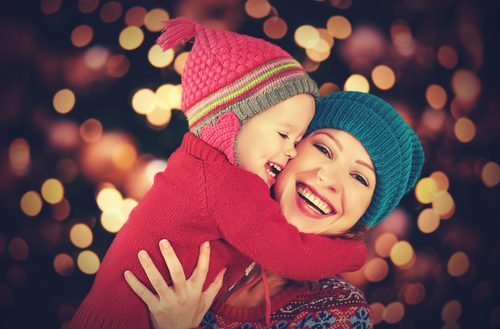 Mother and child hugging, wearing winter hats.