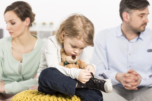 Child between two adults, holding a teddy.