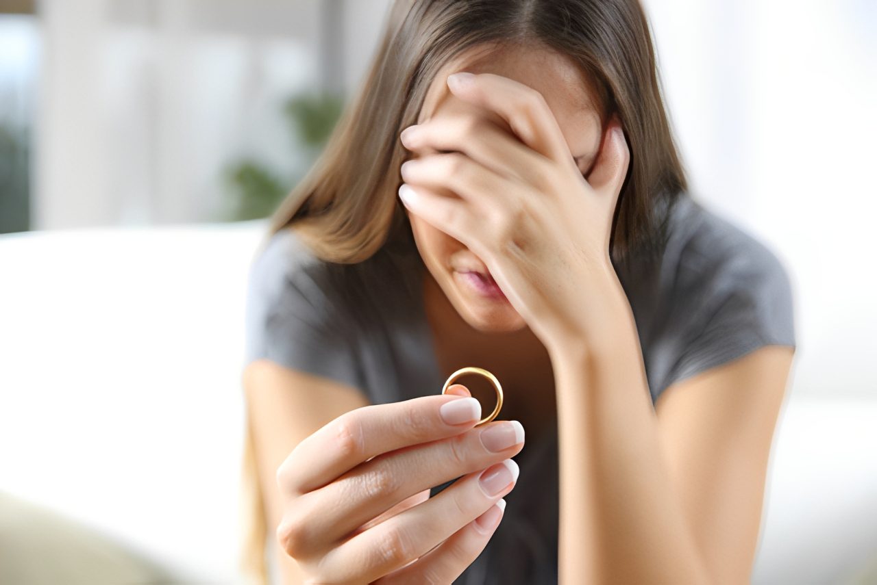 Woman holding ring, looking distressed.