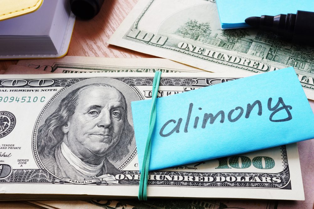 Cash bundle labeled "alimony" with rubber band.