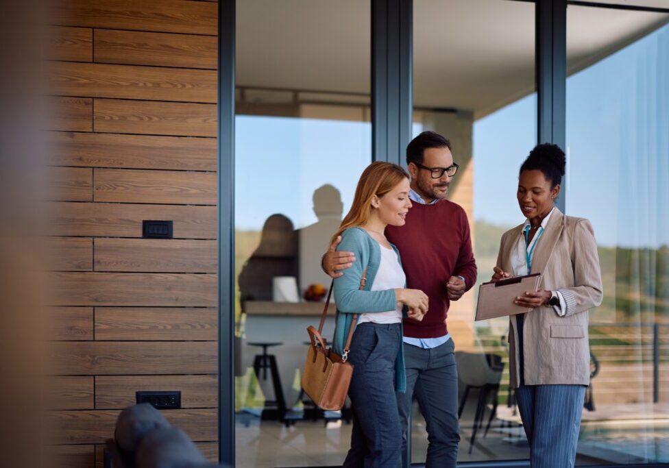 Real estate agent with couple outside modern home.
