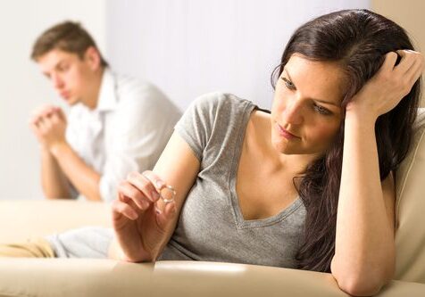 Woman contemplating ring, man in background.
