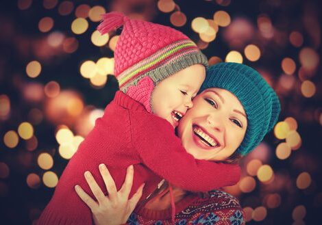 Mother and child hugging, wearing winter hats.