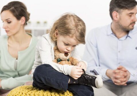 Child between two adults, holding a teddy.