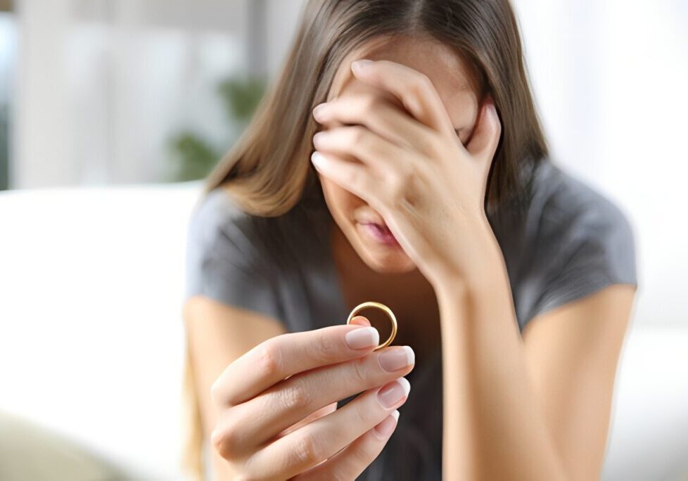 Woman holding ring, looking distressed.