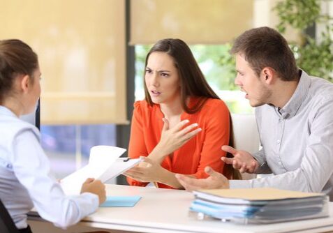 Couple arguing with advisor at desk.